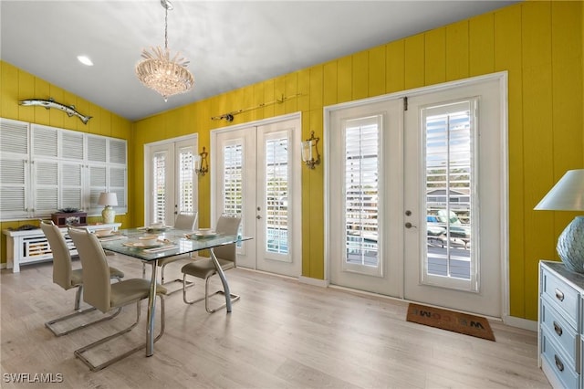 dining room featuring french doors, wooden walls, and a notable chandelier