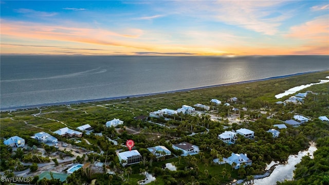 aerial view at dusk with a water view and a view of the beach