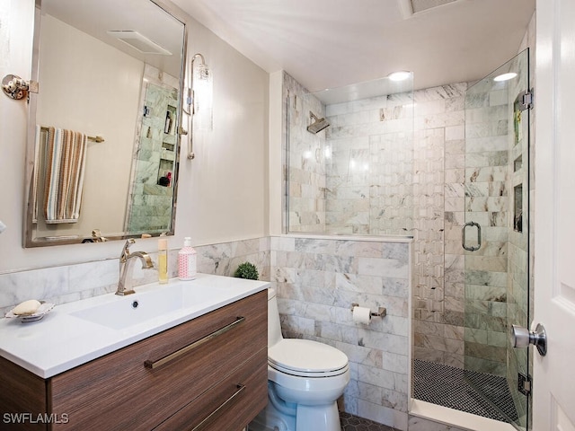 bathroom with an enclosed shower, vanity, toilet, and tile walls