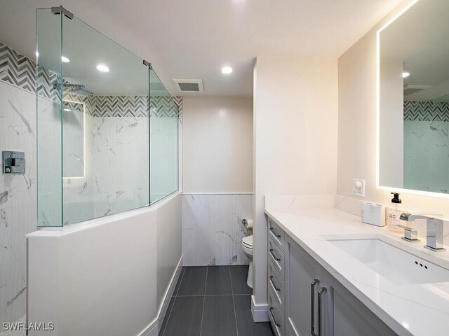 bathroom with tile patterned floors, vanity, toilet, and tiled shower