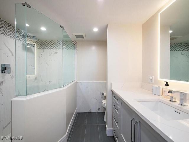 bathroom with tile patterned floors, vanity, toilet, and a tile shower