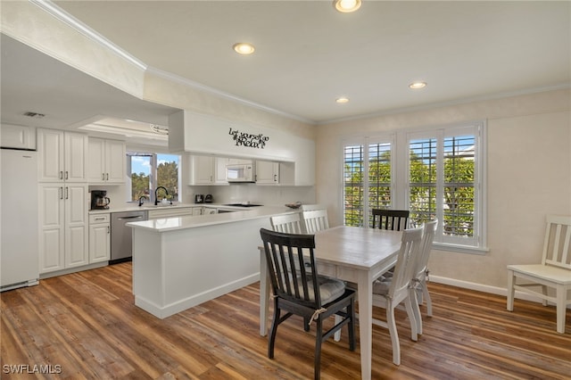 dining area with sink, wood-type flooring, plenty of natural light, and ornamental molding