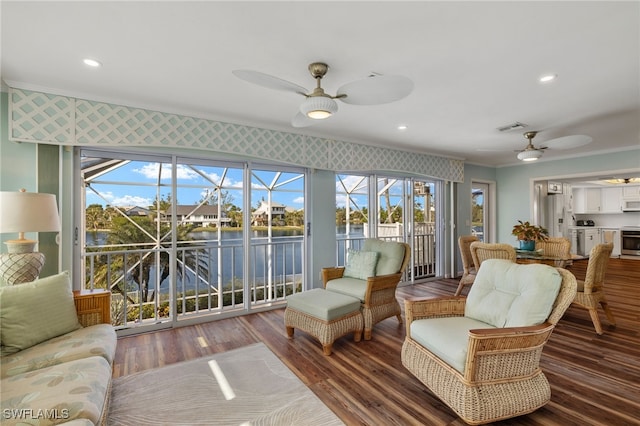 living room with hardwood / wood-style floors, ceiling fan, a water view, and ornamental molding