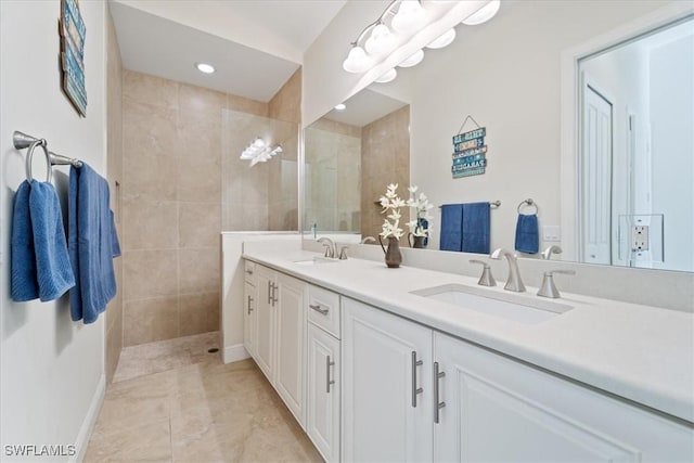 bathroom with tile patterned flooring, a tile shower, and vanity