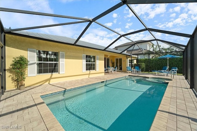 view of pool with a patio, glass enclosure, and an in ground hot tub