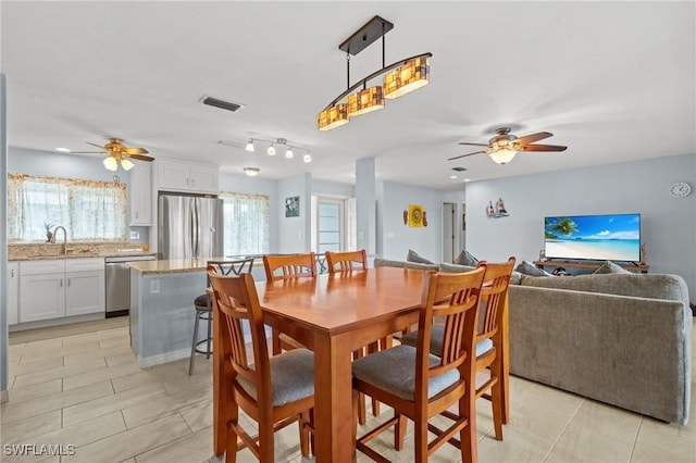 tiled dining space with ceiling fan and sink