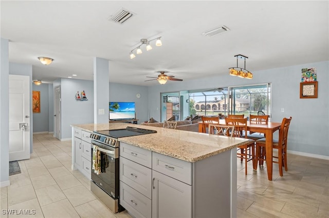 kitchen with light stone countertops, ceiling fan, a kitchen island, hanging light fixtures, and stainless steel electric range