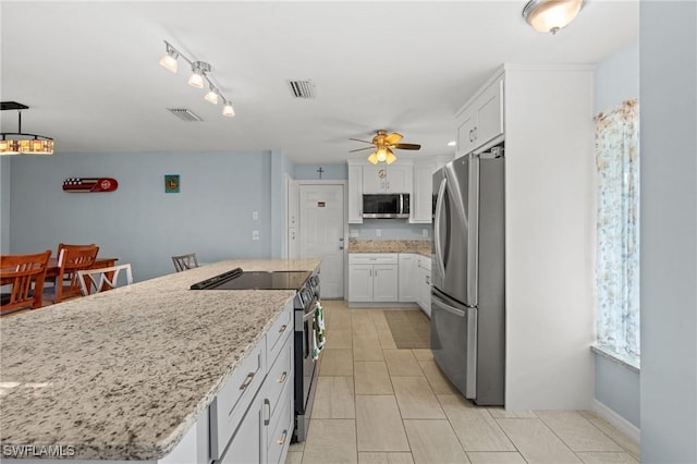 kitchen with white cabinetry, a center island, ceiling fan, stainless steel appliances, and light stone counters