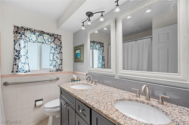 bathroom with a wealth of natural light, vanity, toilet, and tile walls