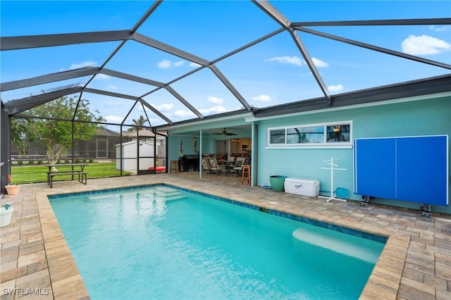 view of pool with ceiling fan, a lanai, a patio, and a shed