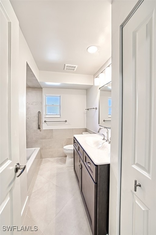 bathroom featuring tile patterned floors, vanity, tile walls, and toilet