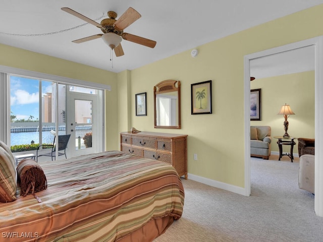 bedroom with access to outside, ceiling fan, a water view, and light carpet