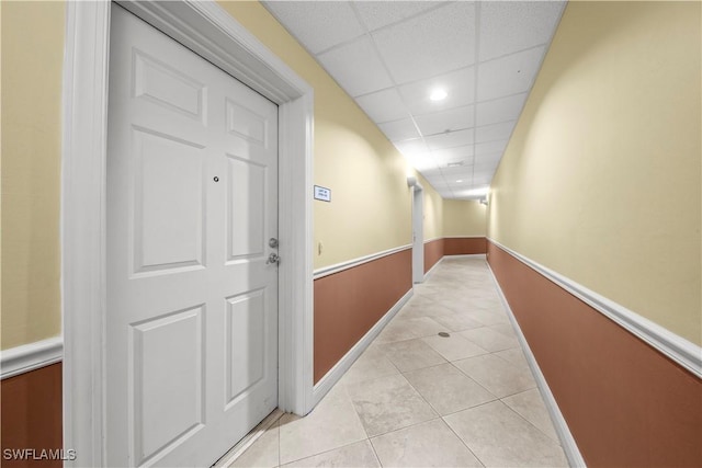 hallway featuring a paneled ceiling and light tile patterned floors