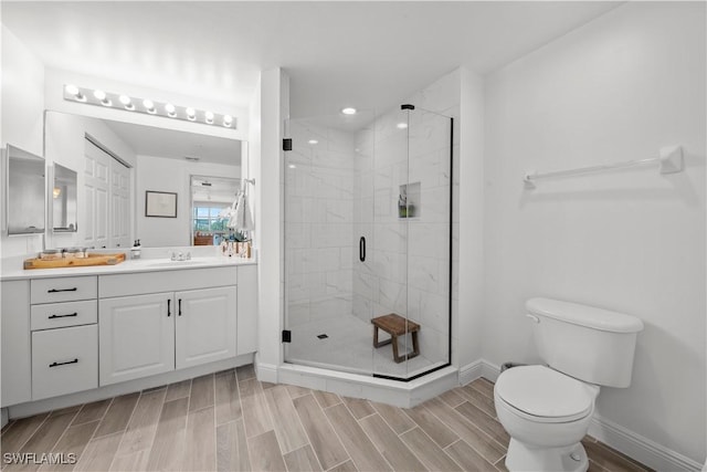 bathroom featuring vanity, toilet, and a shower with door