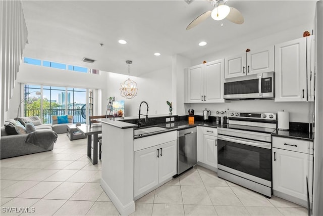 kitchen with pendant lighting, white cabinets, sink, kitchen peninsula, and stainless steel appliances