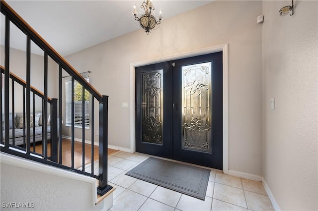 foyer featuring light tile patterned floors, french doors, and a notable chandelier