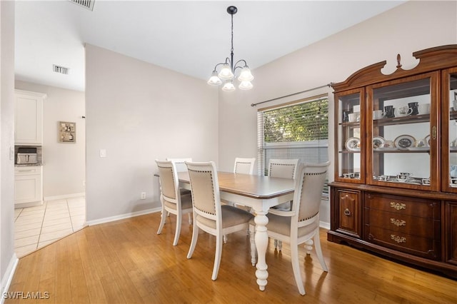 dining room with light wood-type flooring and a chandelier