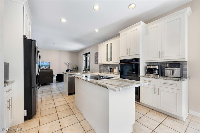 kitchen featuring light stone countertops, white cabinetry, a center island, and black appliances