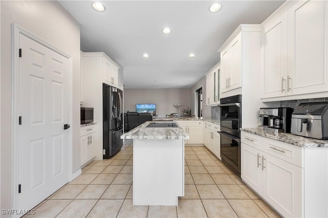 kitchen with a center island, black appliances, white cabinetry, kitchen peninsula, and light stone counters