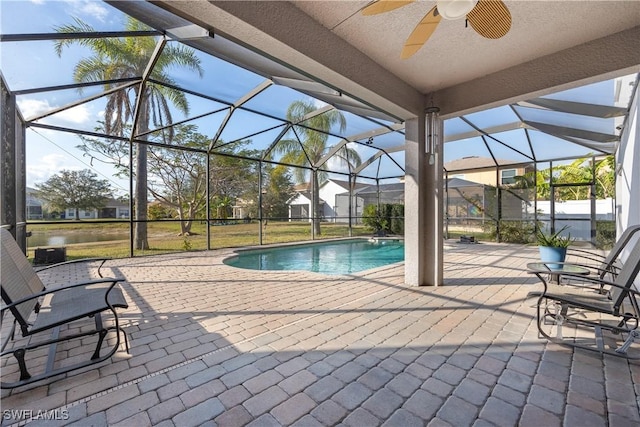 view of swimming pool with ceiling fan, glass enclosure, and a patio