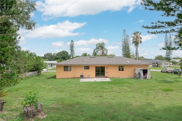 rear view of property with cooling unit and a yard