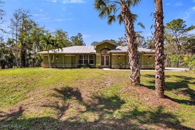 view of front of house with french doors, metal roof, a front lawn, and stucco siding