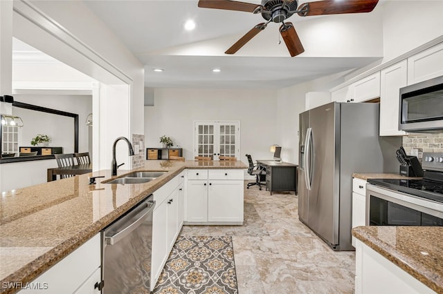 kitchen with white cabinets, decorative backsplash, appliances with stainless steel finishes, light stone counters, and a sink