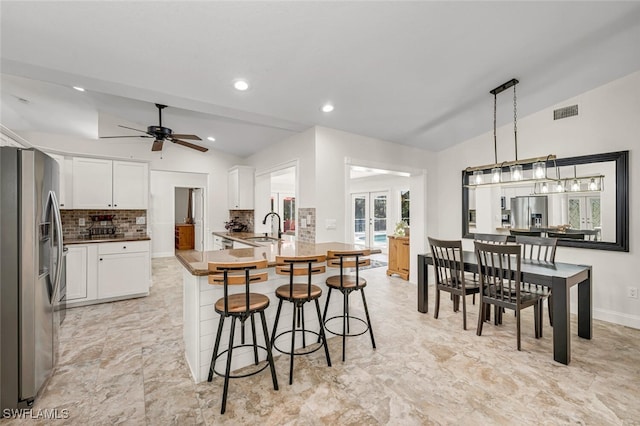 kitchen with lofted ceiling, french doors, a sink, and stainless steel fridge with ice dispenser