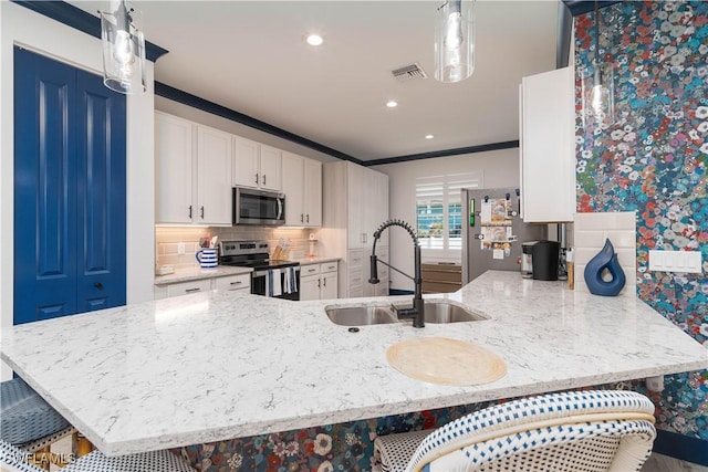 kitchen featuring kitchen peninsula, appliances with stainless steel finishes, tasteful backsplash, ornamental molding, and sink