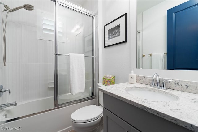 full bathroom featuring vanity, toilet, and bath / shower combo with glass door