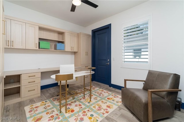 home office with ceiling fan, built in desk, and light hardwood / wood-style flooring