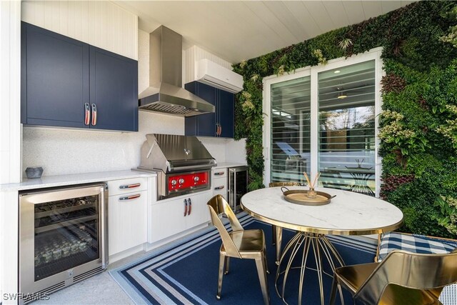 kitchen with backsplash, wall chimney range hood, blue cabinetry, and beverage cooler