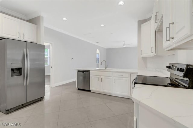 kitchen with light stone countertops, appliances with stainless steel finishes, ornamental molding, sink, and white cabinetry