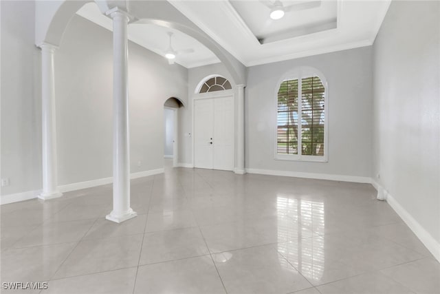 tiled entryway featuring a raised ceiling, ceiling fan, ornamental molding, and ornate columns