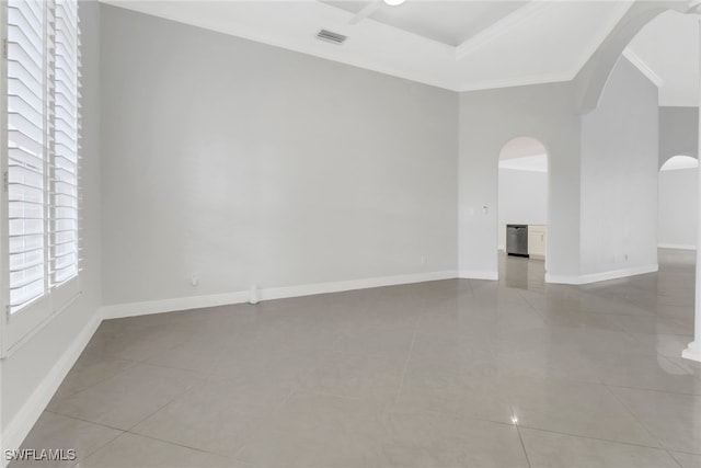 empty room featuring a raised ceiling, crown molding, and light tile patterned flooring