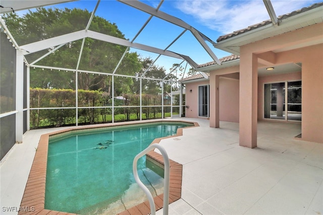 view of swimming pool featuring glass enclosure and a patio