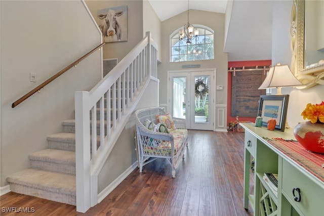 foyer entrance with dark wood-type flooring, french doors, high vaulted ceiling, and a chandelier