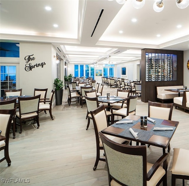 dining space featuring light wood-type flooring and coffered ceiling