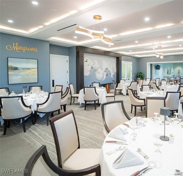 carpeted dining space with a tray ceiling and a chandelier