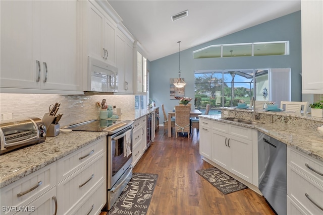 kitchen with sink, vaulted ceiling, decorative backsplash, appliances with stainless steel finishes, and white cabinetry