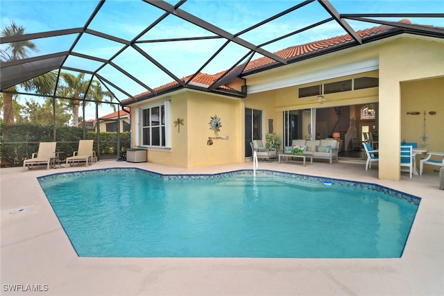 view of pool with an outdoor living space, glass enclosure, ceiling fan, and a patio area