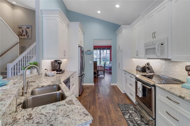 kitchen featuring sink, stainless steel appliances, light stone counters, lofted ceiling, and white cabinets