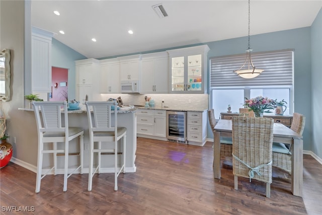 kitchen featuring white cabinetry, light stone countertops, hanging light fixtures, tasteful backsplash, and wine cooler