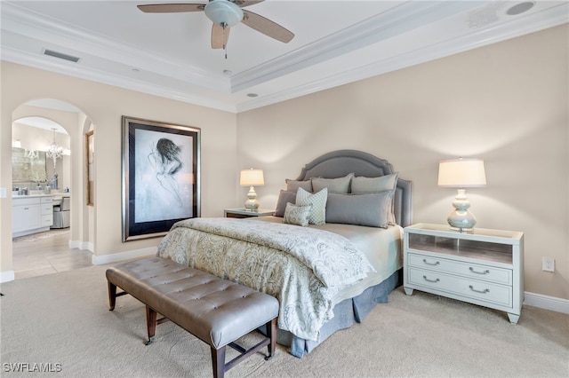 bedroom with ornamental molding, light colored carpet, ceiling fan, and a tray ceiling