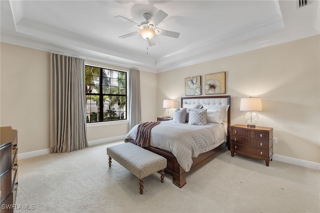 bedroom featuring ceiling fan, light colored carpet, ornamental molding, and a tray ceiling