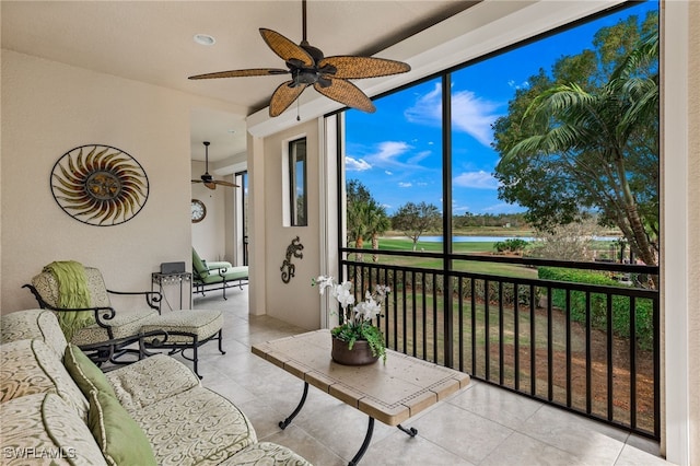 sunroom with ceiling fan and a water view