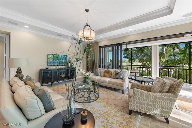 living room with an inviting chandelier, a tray ceiling, and crown molding