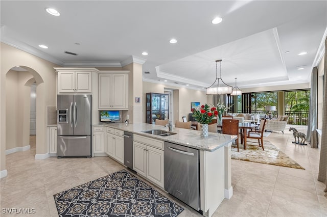 kitchen with pendant lighting, sink, appliances with stainless steel finishes, a raised ceiling, and kitchen peninsula