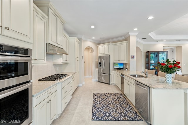 kitchen with sink, appliances with stainless steel finishes, light stone countertops, decorative backsplash, and kitchen peninsula