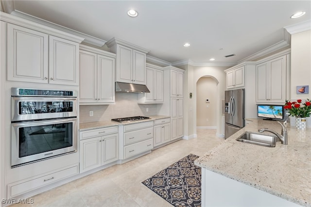 2550 Marquesa Royale Ln Unit 8-101, Naples, FL 34109 - kitchen with crown molding, a sink, arched walkways, stainless steel appliances, and decorative backsplash